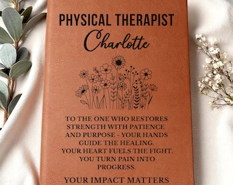 May include: A brown leather-bound journal with the words "PHYSICAL THERAPIST Charlotte" in black lettering. Below the name is a floral design. The journal also includes an inspirational quote about restoring strength and turning pain into progress.