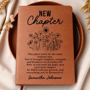 May include: A brown leather journal with the words "NEW Chapter" and a floral design. The journal includes a heartfelt message and the name "Samantha Johnsons" at the bottom. The journal is on a brown plate.