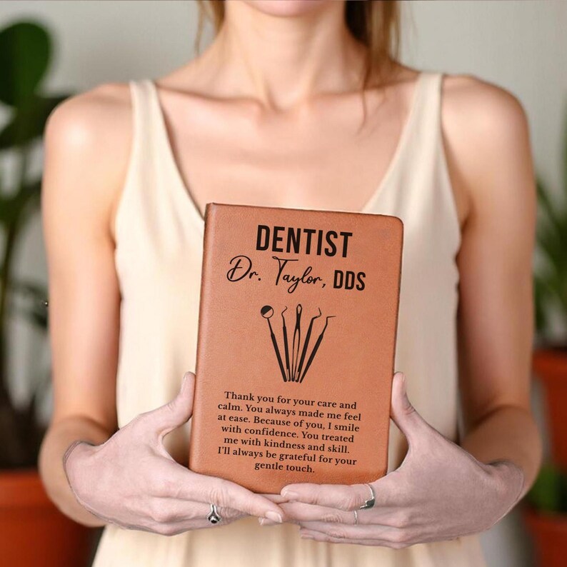 May include: A brown leather-bound notebook with the word "DENTIST" and the name "Dr. Taylor, DDS" printed on the cover. The notebook features dental tools and a thank you message.