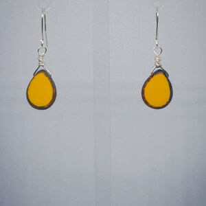 May include: A pair of dangle earrings with yellow glass teardrop-shaped beads and silver wire.