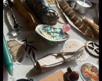 May include: An assortment of spiritual and metaphysical items, including a sage bundle, abalone shell, crystals, candles, and decorative stickers. The items are arranged on a white surface, with natural light illuminating the scene.