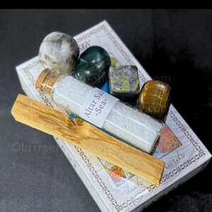 May include: A thoughtful gift set for beginners, featuring a deck of cards, crystals, a bottle of altar sea salt, and a palo santo stick. The crystals are various colors and shapes. The text "A Thoughtful Gift for Beginners" is at the top.