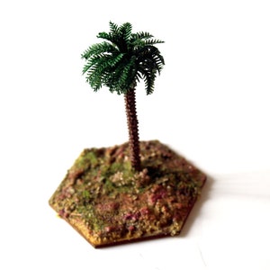 May include: A miniature palm tree with a textured brown trunk and dark green fronds, mounted on a hexagonal base with a mottled brown, green, and tan surface texture that mimics natural terrain for tabletop gaming and scale modeling displays.