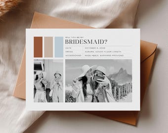 以下が含まれることがあります： 「WILL YOU BE MY BRIDESMAID?」の文字が入った白い招待状と、自撮りをする女性2人の写真。日付、ドレス、アクセサリーの詳細が記載されています。茶色の封筒に入っています。