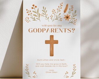 May include: A white card with the text "will you be my GODPARENTS?" in brown. A brown cross is centered below the text. The card includes the names "Aunt Lillian and Uncle Josh" and a message from "Oliver Dean". Floral illustrations in brown and orange decorate the card.
