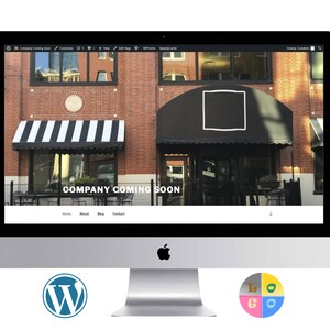 May include: A computer screen displaying a website with the text "COMPANY COMING SOON" on a black background. The website has a menu bar with the words "Home", "About", "Blog", and "Contact". The website is displayed on a silver iMac computer. The computer is sitting on a white surface. There is a WordPress logo on the left side of the computer and a colourful logo on the right side of the computer.