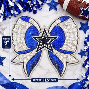May include: A decorative bow ornament featuring a blue and white color scheme with a central navy blue star emblem. The bow is approximately 9 inches tall and 11.5 inches wide, with text indicating these dimensions on the image.