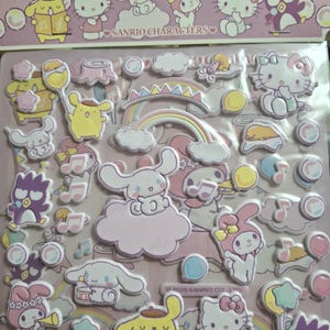 May include: A sheet of puffy stickers featuring Sanrio characters in pastel shades. The stickers include Hello Kitty, My Melody, and other characters, along with musical notes, rainbows, and clouds. The stickers are on a pink background.