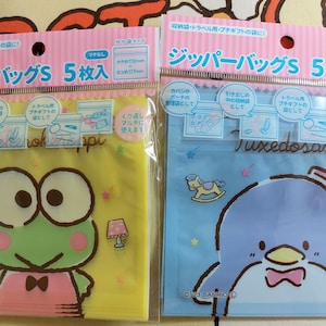 May include: Two packages of zipper bags with a cartoon character on each. The package on the left has a green frog with pink and white clothing. The package on the right has a blue penguin with a pink bow tie. Both packages say "Zipper Bags 5 Pack" and have the text "Tuxedo Sam" on the bottom.