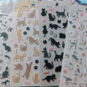 Op de afbeelding: Vier vellen met stickers met verschillende kattenontwerpen. De stickers zijn op een witte achtergrond en hebben verschillende kleuren, waaronder bruin, zwart, wit en grijs. De stickers zijn gelabeld met "NEK non seal".