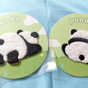 Op de afbeelding: Twee witte en zwarte pandabeer-patches op een groene achtergrond met het woord "panda" op elke patch.