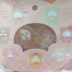 Op de afbeelding: Een roze en witte vel met stickers met schattige cartoonberen met verschillende uitdrukkingen. De stickers zijn in een cirkel gerangschikt rond de woorden "Lots of sweet cute bears!" en "Cute soft fluffy bears!"
