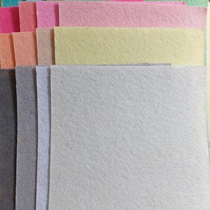 Peut inclure: Une pile de feuilles de feutre de différentes couleurs, notamment bleu clair, vert, rose, jaune et blanc. Les feuilles de feutre sont disposées en arc-en-ciel.
