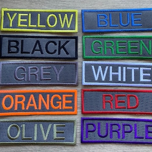 May include: Ten fabric patches with different colours and text. The colours are yellow, blue, black, green, grey, white, orange, red, olive, and purple. The text on each patch is the name of the colour.