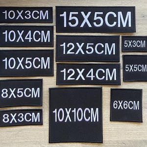 May include: A collection of black rectangular patches with white text indicating dimensions in centimeters. Sizes range from 5x3cm to 15x5cm. The patches are arranged on a light-colored surface.