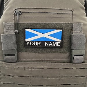 Puede incluir: Un chaleco táctico gris con un parche de velcro con la bandera de Escocia y el texto "YOUR NAME".