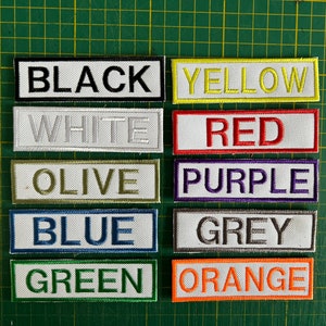 Puede incluir: Diez parches de tela de diferentes colores con el nombre del color escrito en blanco en cada parche. Los colores son negro, amarillo, blanco, rojo, oliva, morado, azul, gris, verde y naranja.