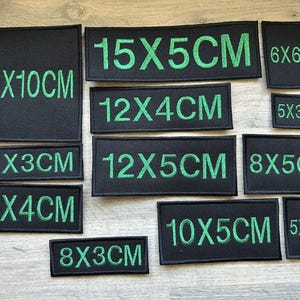 May include: A collection of black fabric patches with green embroidered text indicating different sizes in centimetres. The sizes include 10x10cm, 15x5cm, 12x4cm, 10x3cm, 12x5cm, 8x5cm, 10x4cm, 10x5cm, 8x3cm, 6x6cm, 5x3cm, and 5x5cm.