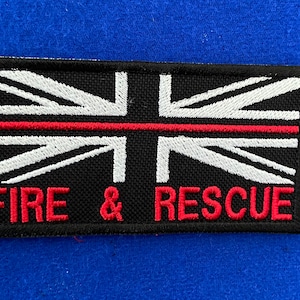 May include: A black and white embroidered patch with a red stripe across the middle. The patch features the Union Jack flag and the words "FIRE & RESCUE" in red.