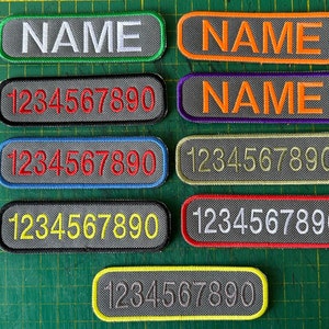 May include: Eight grey fabric patches with different coloured borders. The patches have either the word "NAME" or the numbers "1234567890" printed on them.