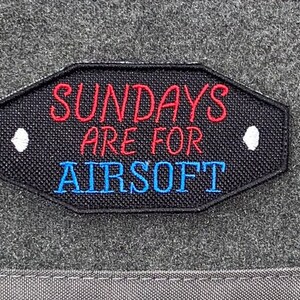 以下が含まれることがあります： 白いステッチと「SUNDAYS ARE FOR AIRSOFT」という赤い文字と青い文字が書かれた黒いパッチ