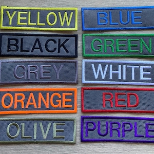 May include: Ten fabric patches with different colours and text. The colours are yellow, blue, black, green, grey, white, orange, red, olive, and purple. The text on the patches reads "YELLOW", "BLUE", "BLACK", "GREEN", "GREY", "WHITE", "ORANGE", "RED", "OLIVE", and "PURPLE".