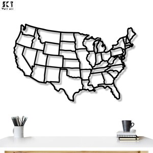 May include: Black metal wall art depicting the outline of the United States, with each state's borders clearly defined. The artwork is mounted on a white wall, with a shadow effect adding depth. The logo "SKY WALL ART" is in the top left corner.