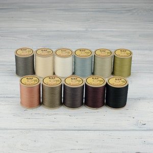 May include: Twelve spools of thread in various colors, including beige, brown, gray, and green. Each spool is labeled with the number "632" and the name of the color.