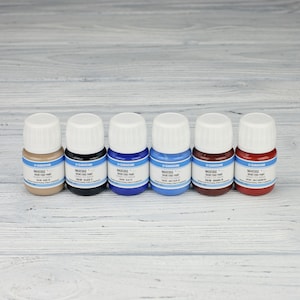 Puede incluir: Seis peque&ntilde;os frascos de tinte para cuero en varios colores, incluyendo marr&oacute;n, negro, azul, azul claro, rojo y burdeos. Cada frasco tiene una etiqueta blanca con el nombre de la marca "GARDINI" y el texto "MAXEDGE BASIC EDGE PAINT".