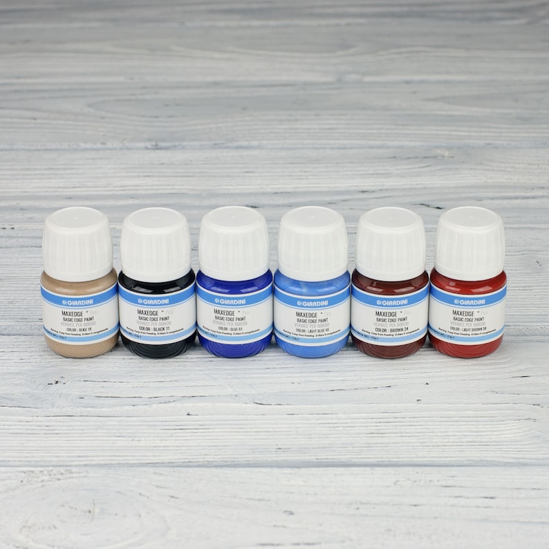 Puede incluir: Seis peque&ntilde;os frascos de tinte para cuero en varios colores, incluyendo marr&oacute;n, negro, azul, azul claro, rojo y burdeos. Cada frasco tiene una etiqueta blanca con el nombre de la marca "GARDINI" y el texto "MAXEDGE BASIC EDGE PAINT".