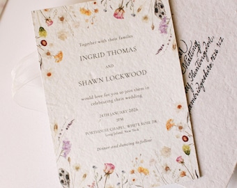May include: A rectangular wedding invitation printed on textured off-white paper featuring a delicate border of watercolor wildflowers in shades of pink, yellow, and green. The text reads Ingrid Thomas and Shawn Lockwood, 24th January 2026, 2PM.