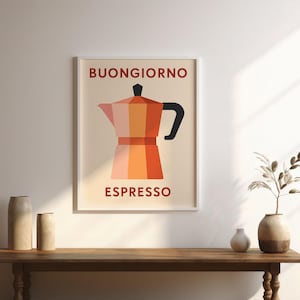 Puede incluir: Un cuadro enmarcado con una cafetera estilizada en tonos naranja y rojo, con las palabras "BUONGIORNO" y "ESPRESSO" en rojo. El cuadro está sobre una mesa de madera con jarrones decorativos.