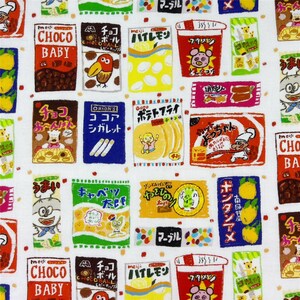 以下が含まれることがあります： 日本の様々なスナック菓子のパッケージが繰り返される白い生地。日本語のテキスト、漫画のキャラクター、チョコレート、チップス、キャンディなどのイラストが描かれたカラフルな箱や袋のデザインが特徴です。