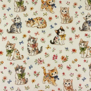 May include: A cream-colored fabric featuring a repeating pattern of kittens in various poses, each wearing a decorative bow or floral accessory. The kittens are interspersed with small, colorful floral clusters and tiny blue butterflies.