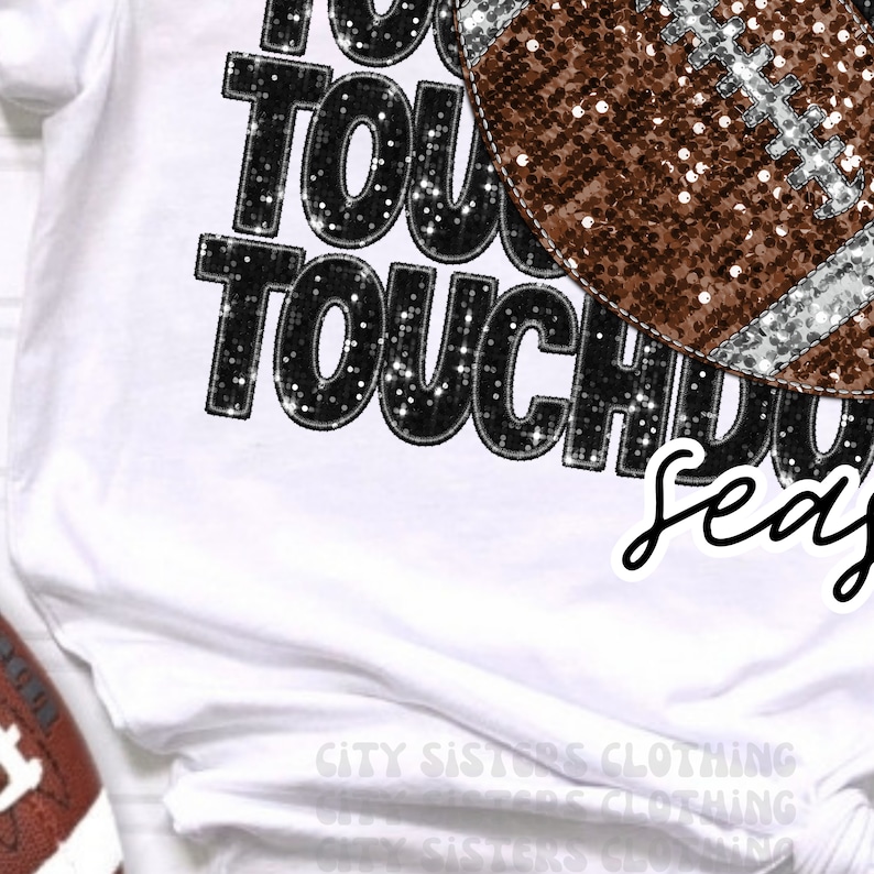 May include: White t-shirt with black glitter text that says "Touchdown Season" with a brown and silver glitter football graphic.