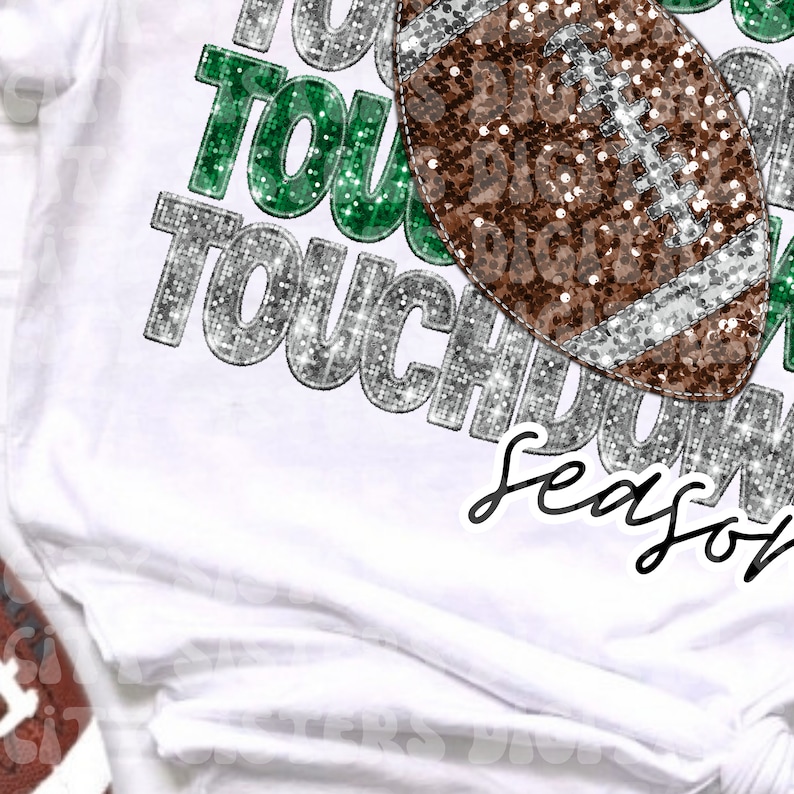 Op de afbeelding: Een wit T-shirt met een glinsterend zilver en groen "Touchdown Season" ontwerp. Een bruine en zilveren glitter voetbal is te zien in het ontwerp.