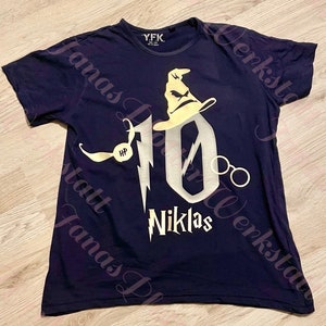 Pu&ograve; includere: Una maglietta blu navy con un designo di glitter dorati del numero 10, un cappello da mago, occhiali e un boccino d'oro. Il testo "Niklas" &egrave; sotto il numero 10.