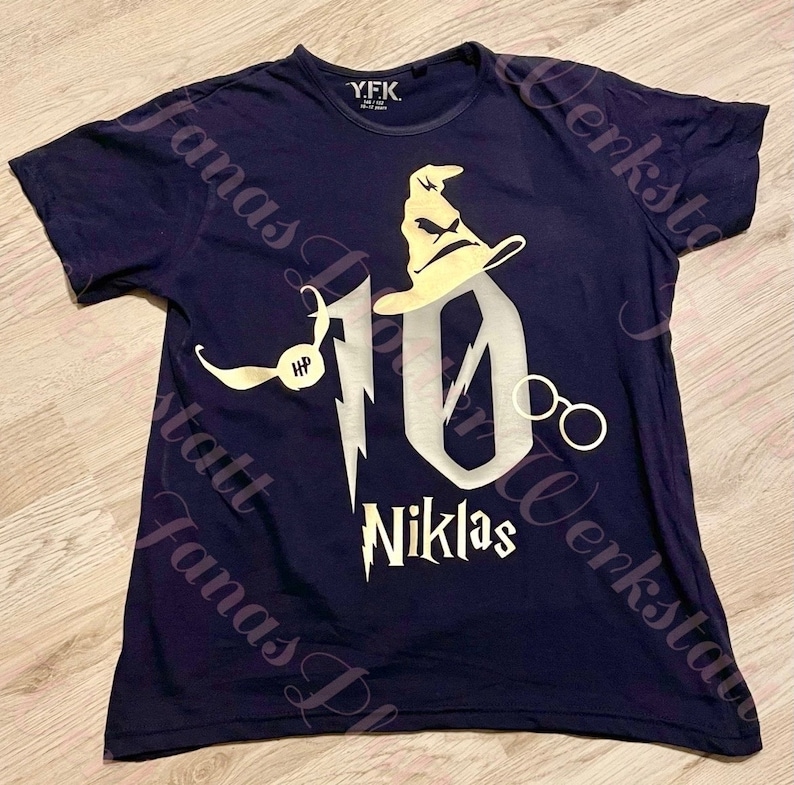 Pu&ograve; includere: Una maglietta blu navy con un designo di glitter dorati del numero 10, un cappello da mago, occhiali e un boccino d'oro. Il testo "Niklas" &egrave; sotto il numero 10.