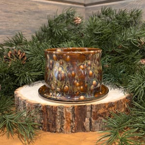 May include: A white ceramic mug with a black handle and the text "But First, Coffee" in a bold, black font. The mug is set against a blurred background, highlighting its clean design.