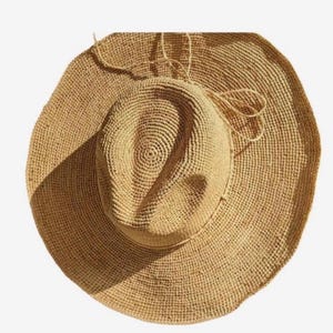 Pode incluir: Um chap&eacute;u de palha de aba larga com uma textura tecida marrom. O chap&eacute;u tem uma fita amarrada ao redor da coroa.