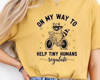 On My Way to Help Tiny Humans Regulate Shirt, Funny Kindergarten Teacher Raccoon Tee