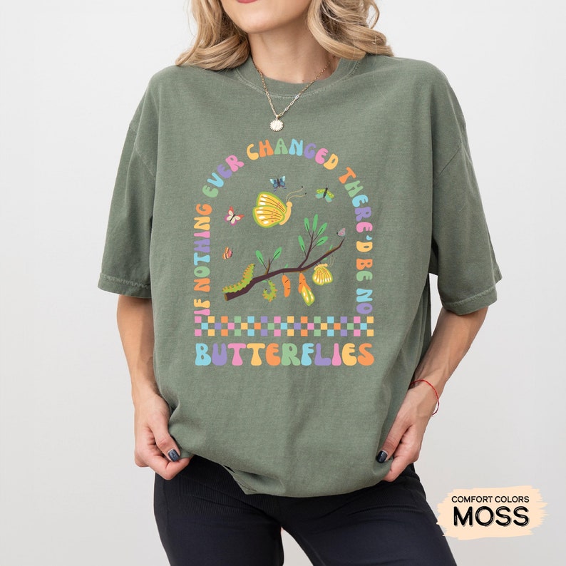 K&ouml;nnte beinhalten: Gr&uuml;nes T-Shirt mit einem Motiv eines Zweigs mit Schmetterlingen und Raupen. Der Text auf dem Shirt lautet "If nothing ever changed there'd be no butterflies".