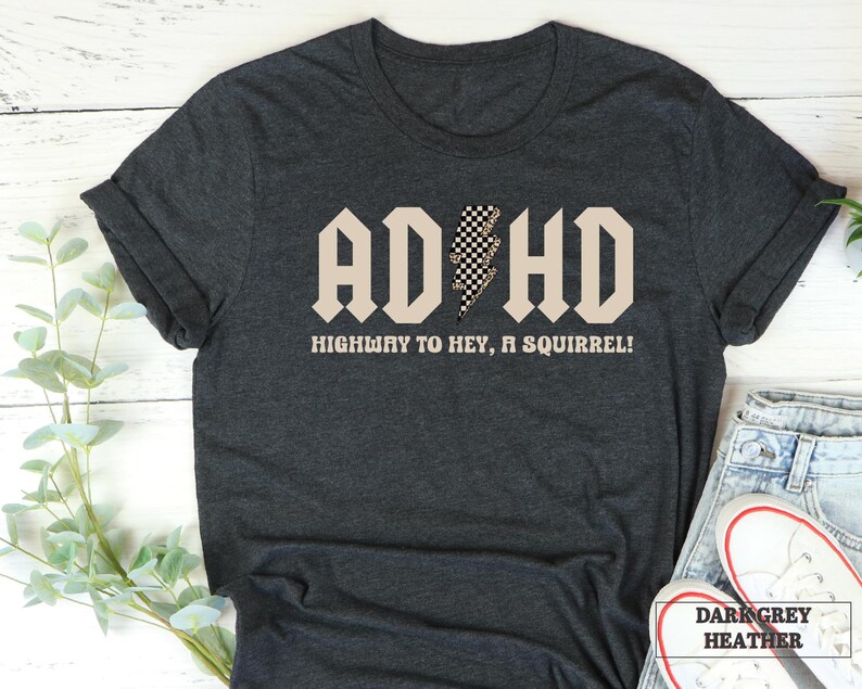 May include: Dark grey heather t-shirt with a black and white checkered lightning bolt graphic and the text "ADHD HIGHWAY TO HEY, A SQUIRREL!"