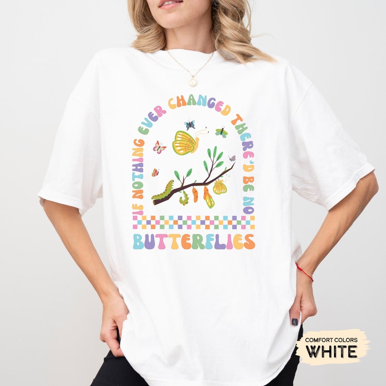 K&ouml;nnte beinhalten: Wei&szlig;es T-Shirt mit einem bunten Grafikdesign, das einen Zweig mit Schmetterlingen, Raupen und Kokons zeigt. Der Text "If nothing ever changed there'd be no butterflies" ist in einem Regenbogenbogen um die Grafik geschrieben.