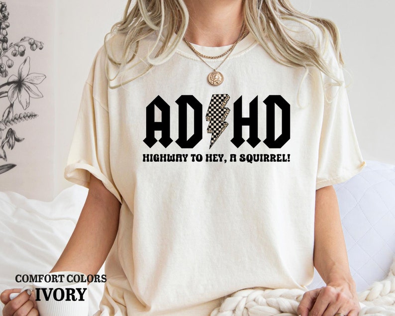 May include: Ivory t-shirt with a black graphic that says "ADHD Highway to Hey, a Squirrel!" with a checkered lightning bolt.