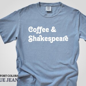 May include: A light blue t-shirt with the text "Coffee & Shakespeare" in white. The shirt is made of a soft, comfortable material.