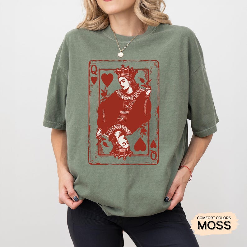 May include: A green t-shirt with a red graphic of the Queen of Hearts playing card. The graphic features a stylized image of a queen holding a heart and a rose.