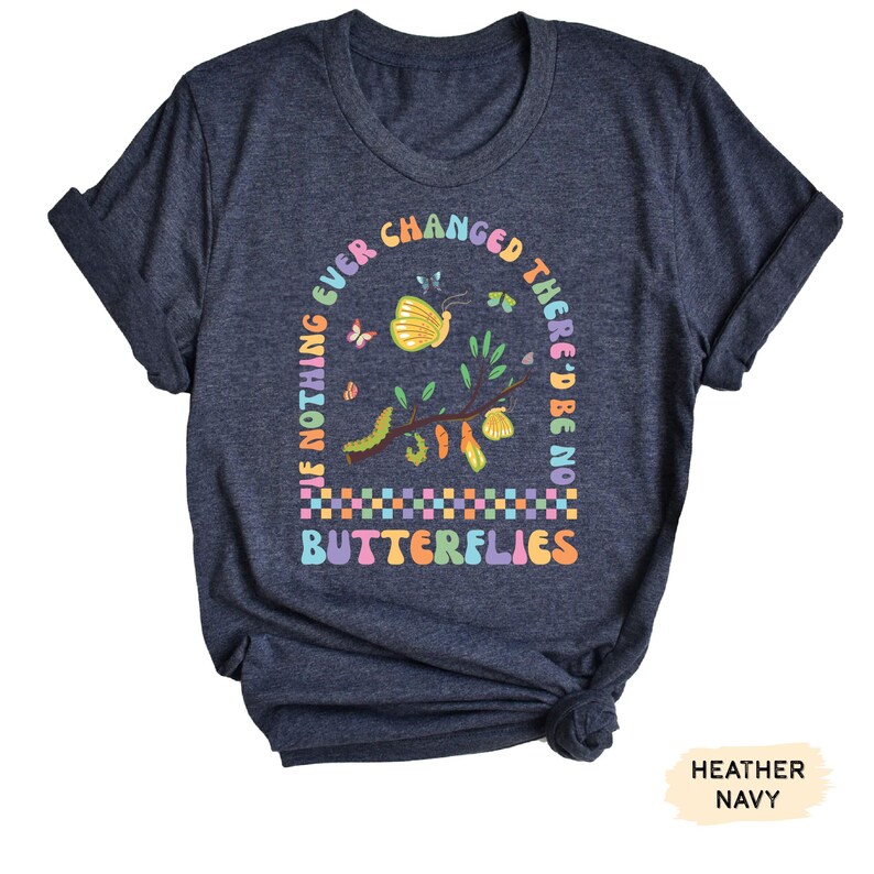 K&ouml;nnte beinhalten: Ein heidefarbenes marineblaues T-Shirt mit einer bunten Grafik eines Zweigs mit Schmetterlingen und Raupen. Der Text auf dem Shirt lautet "If nothing ever changed there'd be no butterflies".