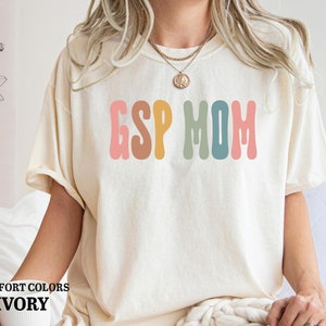 a woman sitting on a bed wearing a t - shirt that says esp mom