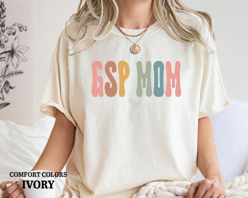 a woman sitting on a bed wearing a t - shirt that says esp mom